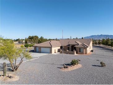 Wide shot of a desert home with gravel landscaping, a three-car garage, and a mountain view at 1361 Moose St, Pahrump, NV 89048