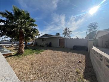 View of the gravel-filled backyard with a palm tree and a block wall at 1429 S Sandhill Rd, Las Vegas, NV 89104