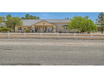 Charming single-story home with a white fence, gravel driveway, and mature trees providing shade and curb appeal at 3231 Rebel Ave, Pahrump, NV 89048