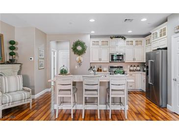 Bright kitchen features white cabinets, stainless appliances, island with breakfast bar and wood floors at 3185 Mura Del Prato Ave, Henderson, NV 89044