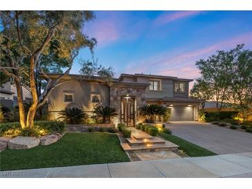 Beautiful two-story home with stone accents, manicured landscaping, and illuminated walkway leading to the front entrance at 9 Clear Crossing Trl, Henderson, NV 89052
