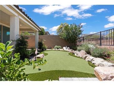 Landscaped backyard featuring a putting green, desert plants, and privacy fence at 10416 Skye Arroyo Ave, Las Vegas, NV 89166