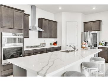 Modern kitchen featuring gray cabinets, stainless steel appliances, and an island with marble countertops at 1596 Pacific Baza St, Las Vegas, NV 89138