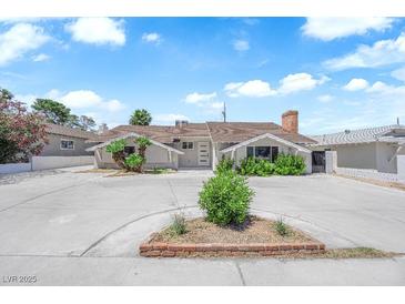 Charming single-story home featuring a spacious front yard with mature landscaping and a large driveway at 1905 E Oakey Blvd, Las Vegas, NV 89104