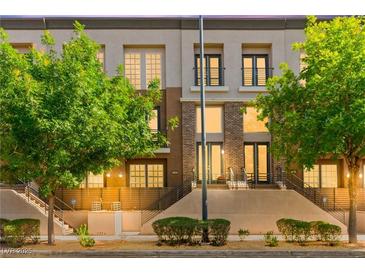 Inviting multi-level home featuring a blend of neutral tones, brick accents, and lush landscaping at 3159 Via Como, Henderson, NV 89044