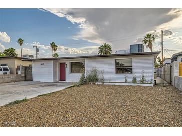 Charming single-story home featuring a minimalist front yard, unique front door, and palm trees on a sunny day at 613 Stanford St, Las Vegas, NV 89107