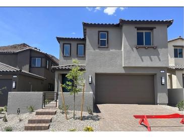 Two-story home featuring a two-car garage, gray stucco, and a landscaped front yard with steps leading to the entry at 72 Via Montoro, Henderson, NV 89011