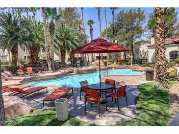 Inviting community pool featuring lounge chairs, tables, mature landscaping, and a rock waterfall feature at 2975 Bluegrass Ln # 811, Henderson, NV 89074