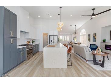 Open-concept kitchen with waterfall island, stainless steel appliances and pendant lighting at 4176 Demoline Cir, Las Vegas, NV 89141