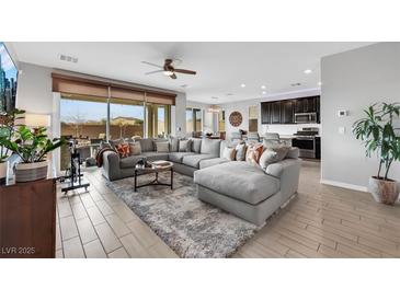 Spacious living room featuring an oversized sectional sofa, and an open layout to the kitchen at 7115 Calvert Cliffs St, North Las Vegas, NV 89084