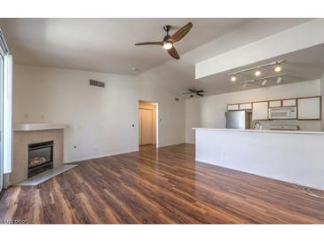 Bright living room with fireplace, ceiling fan and wood floors open to kitchen with stainless steel appliances at 4960 Harrison Dr # 214, Las Vegas, NV 89120