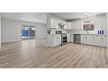 Modern kitchen features white cabinets, stainless steel appliances, and wood-look flooring at 6229 Cromwell Ave, Las Vegas, NV 89107