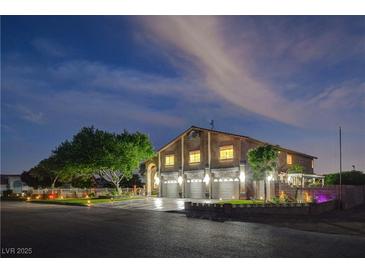 Charming two-story home with three-car garage, lush tree, and illuminated façade at twilight at 7761 Cowboy Trl, Las Vegas, NV 89131