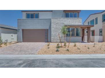 Two-story home with a modern exterior, stone accents, a brick driveway, and a two-car garage at 9265 Frazer St, Las Vegas, NV 89166