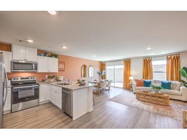 Open-concept kitchen and living room with stainless steel appliances and wood flooring at 2514 Petunia Garden Ave # 226, North Las Vegas, NV 89081