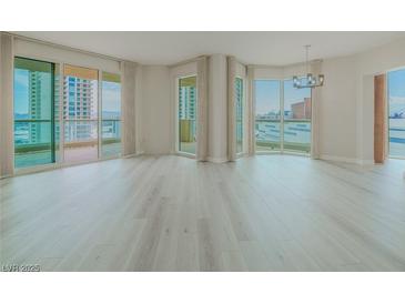 Bright, open living room features light wood floors, neutral walls and multiple windows with city views at 2747 Paradise Rd # 2305, Las Vegas, NV 89109