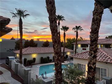 Charming community pool surrounded by lush landscaping and red tile roofs, under a beautiful sunset sky at 3420 Winterhaven St # 202, Las Vegas, NV 89108