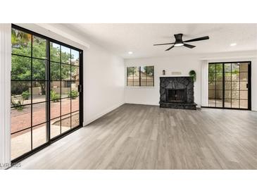 Bright living room with modern floors, sliding glass doors, and a stone fireplace at 3484 Nightflower Ln # 2, Las Vegas, NV 89121