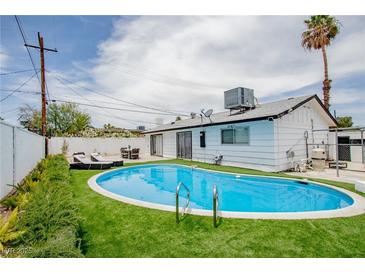 Backyard features a sparkling blue pool surrounded by lush green turf and complimented by lounge chairs at 6301 Garwood Ave, Las Vegas, NV 89107