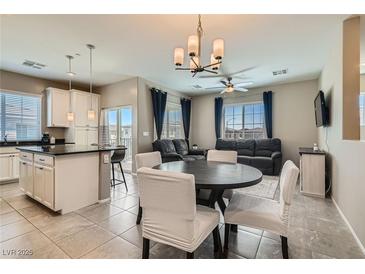 Bright open-concept living and dining area with modern lighting, tile floors, and comfortable seating arrangements at 8490 Classique Ave # 101, Las Vegas, NV 89178