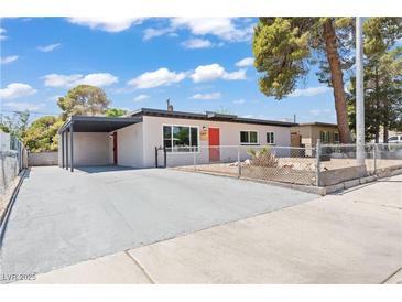 Charming single-story home featuring a carport, xeriscaping, and a vibrant red front door at 1417 Dogwood Ave, North Las Vegas, NV 89030