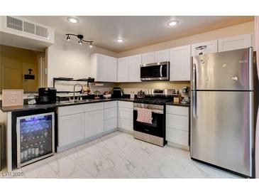 Well-equipped kitchen with sleek white cabinetry, stainless steel appliances, and a built-in beverage cooler at 3322 Dragon Fly St, North Las Vegas, NV 89032