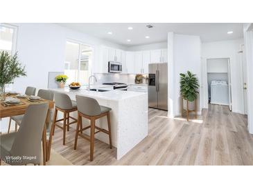 Bright, eat-in kitchen featuring stainless steel appliances, a large island, and a dedicated laundry area at 669 Elliot Peak Ave, Las Vegas, NV 89183