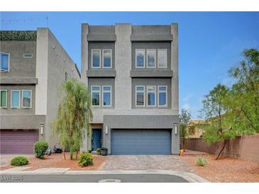 Contemporary two-story home featuring a grey stucco facade, a two-car garage, and a well-manicured front yard with brick pavers at 7756 Seville Estates Ct, Las Vegas, NV 89113