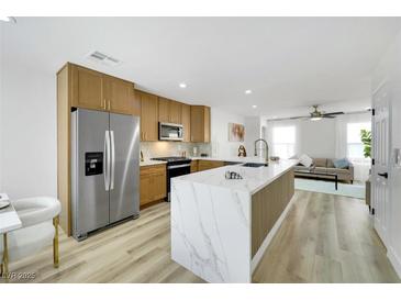 Modern kitchen with stainless steel appliances and a large marble island that opens to the living room at 9078 Hilverson Ave, Las Vegas, NV 89148