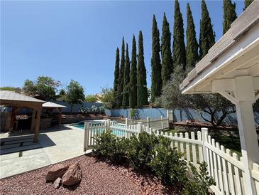 Inviting backyard featuring a fenced pool, covered patio and lush landscaping offering a private outdoor retreat at 9436 Darwell Dr, Las Vegas, NV 89117