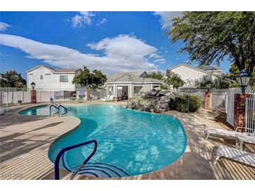 Resort-style pool with rock waterfall feature, lounge chairs, and nearby cabana for relaxing on a sunny day at 10360 Cherry Brook St, Las Vegas, NV 89183