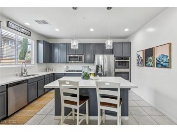 Modern kitchen with stainless steel appliances, gray cabinets, and a center island with white countertop at 160 Lilt Ave, Henderson, NV 89011