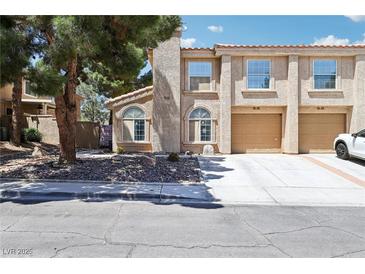 Charming townhome featuring a two-car garage and desert landscaping with mature trees at 2830 Crystal Lantern Dr, Henderson, NV 89074