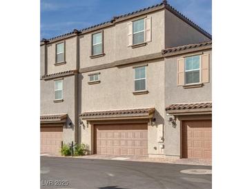Three-story townhome with two car garage and neutral stucco, roof and doors at 538 Ylang Pl, Henderson, NV 89015