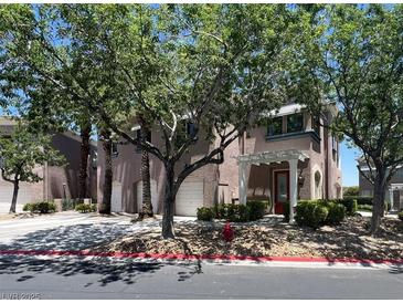 Charming townhome with a two-car garage and covered entryway, surrounded by lush greenery at 9116 Vista Greens Way # 104, Las Vegas, NV 89134