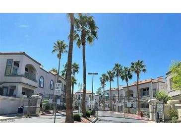 Gated community entrance featuring palm trees and well-maintained buildings under a bright blue sky at 3125 N Buffalo Dr # 2104, Las Vegas, NV 89128