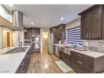 Modern kitchen with stainless steel appliances, wood floors, and large pantry at 8932 Beach Front Dr, Las Vegas, NV 89117
