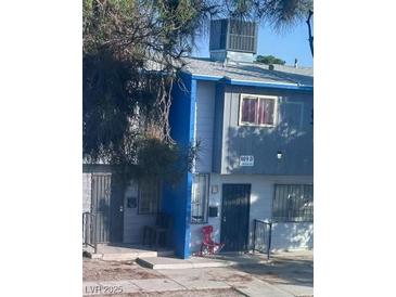 Modest two-story townhome featuring a painted blue accent wall, and a well-lit exterior, providing a cozy, inviting curb appeal at 809 E Cartier Ave # D, North Las Vegas, NV 89030