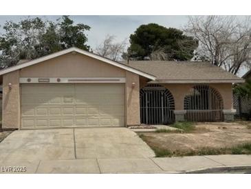 Single story house with a two car garage and gated front porch in need of some TLC at 2450 Oak Glen Way, Las Vegas, NV 89115
