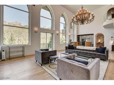 Bright living room featuring high ceilings, large windows, and a decorative chandelier at 4162 Matterhorn Way, Las Vegas, NV 89124