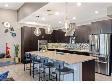 Modern kitchen featuring dark cabinetry, stainless steel appliances, pendant lighting and a spacious island with seating at 4290 Solace St, Las Vegas, NV 89135