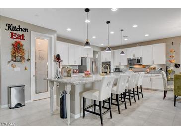Bright kitchen featuring a large island with white cabinets, granite countertops, and stainless steel appliances at 348 Cadence Vista Dr, Henderson, NV 89011