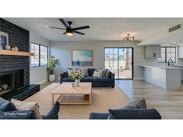 Bright living room with black fireplace, ceiling fan, and sliding door access to the outside at 3484 Nightflower Ln # B, Las Vegas, NV 89121