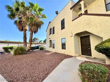 Inviting two-story condo featuring desert landscaping with mature palm trees near the entry at 6137 W Oakey Blvd # A, Las Vegas, NV 89146