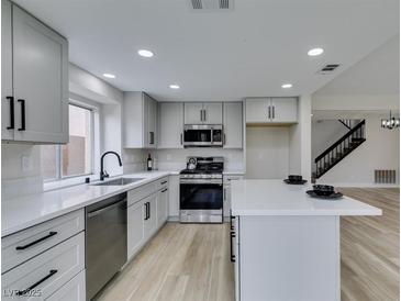 Bright kitchen features sleek countertops, stainless steel appliances, and island, plus modern cabinetry and fixtures at 71 Sea Holly Way, Henderson, NV 89074
