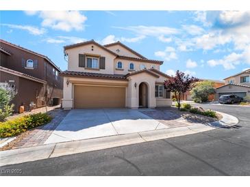 Two-story tan house with a two-car garage, arched entryway and a well-maintained front yard at 11238 Meadow Cove St, Las Vegas, NV 89179
