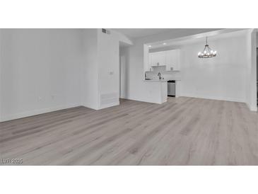 Bright living room with modern light fixture, white walls, and light wood flooring that connects to a modern kitchen at 3318 N Decatur Blvd # 1035, Las Vegas, NV 89130