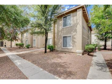 Beige two story home with trees, bushes, and gravel landscape in front at 7200 Pirates Cove Rd # 2084, Las Vegas, NV 89145