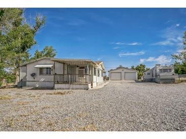 Exterior view of a single-story home with a gravel yard and a detached two-car garage at 960 Third St, Pahrump, NV 89048