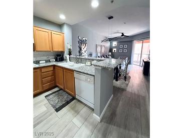 Well-lit kitchen featuring wood cabinets, stainless steel appliances, and an adjacent dining area at 23 E Agate Ave # 301, Las Vegas, NV 89123